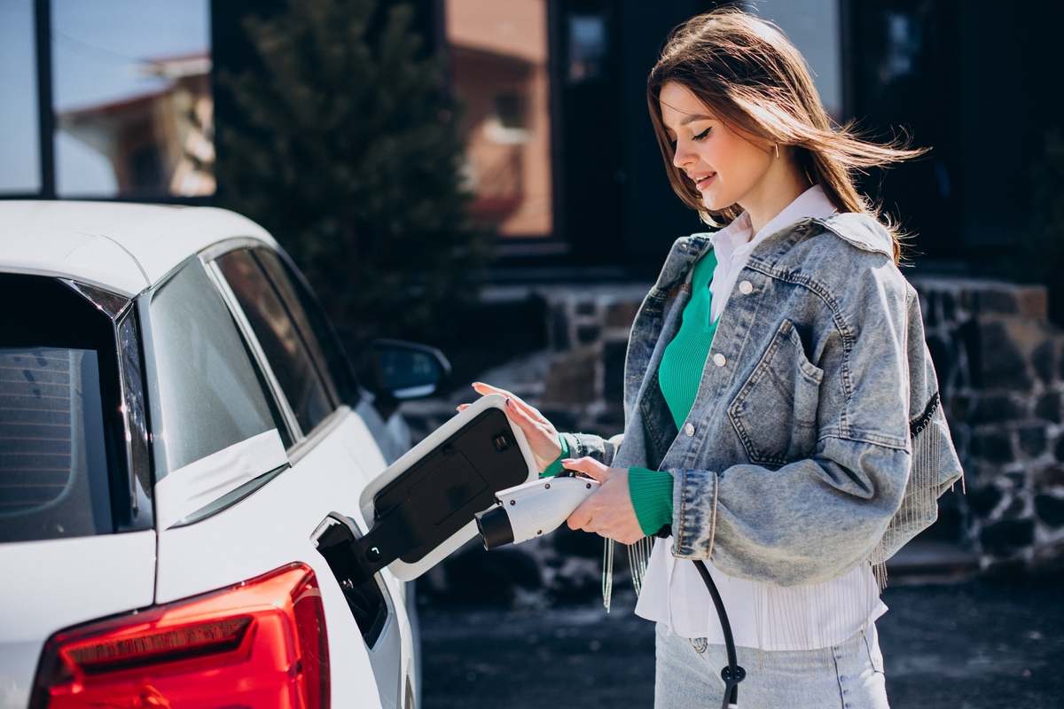 Una ragazza ricarica un'auto elettrica