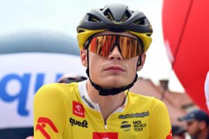 Jonas Vingegaard in primo piano e in maglia gialla, casco e occhiali da sole